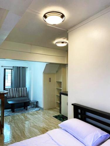a bedroom with a bed and a living room with a couch at Espazzi Apartment in Tacloban