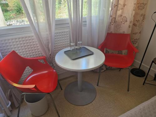 - une table avec deux chaises rouges et un ordinateur portable dans l'établissement Comfortable rooms for Working - Levallois, à Levallois-Perret