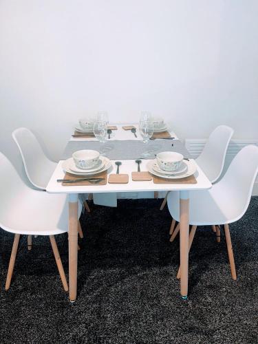a white table with chairs and plates and wine glasses at Bay Wind Apartment in Morecambe