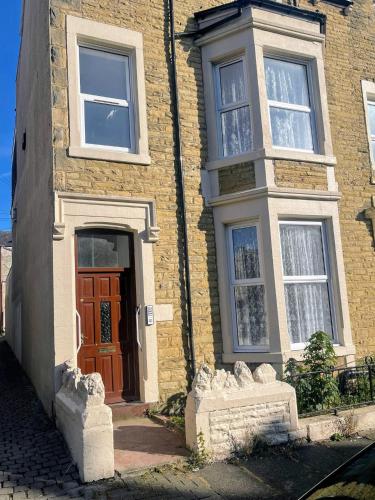 a brick building with a brown door and windows at Bay Wind Apartment in Morecambe