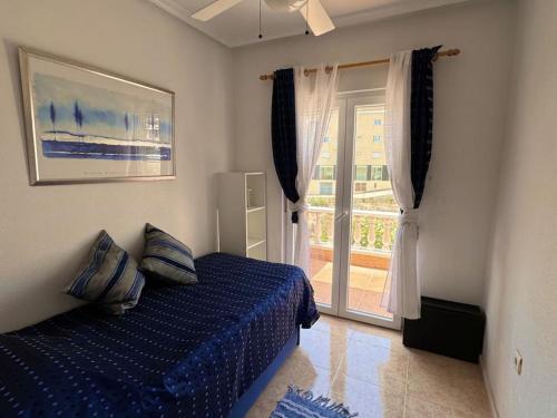 a bedroom with a blue bed and a sliding glass door at House in Orihuela Costa La Zenia in Orihuela