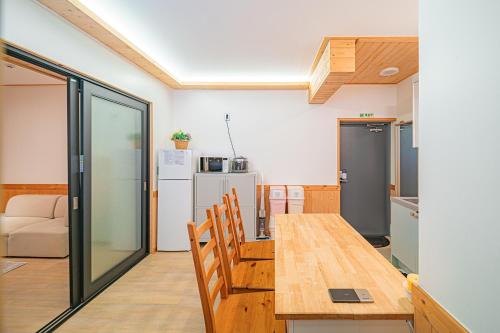 a kitchen and dining room with a wooden table and chairs at Le Village Aewol building A in Jeju