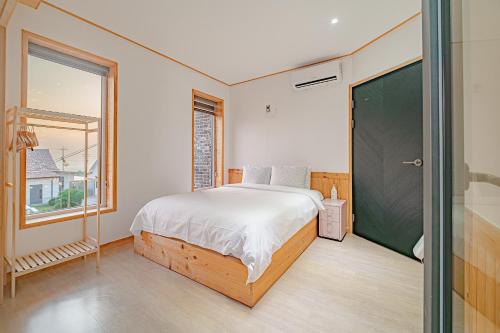 a bedroom with a bed and a large window at Le Village Aewol building A in Jeju