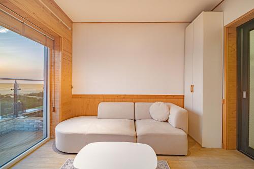 a living room with a white couch and a window at Le Village Aewol building A in Jeju