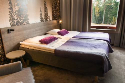 a bedroom with a large bed with purple pillows at Hotel Korpilampi in Espoo