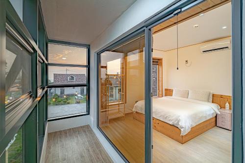a bedroom with a bed and sliding glass doors at Le Village Aewol building A in Jeju
