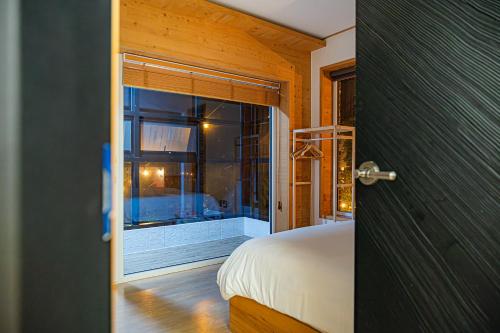 a door to a bedroom with a bed and a window at Le Village Aewol building A in Jeju