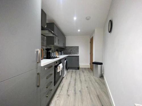 a kitchen with white cabinets and a wooden floor at Apartment 3 in Manchester