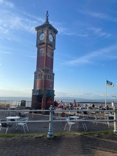 a clock tower with tables and chairs in front of it at Bay Wind Apartment in Morecambe