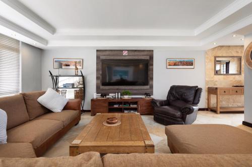 a living room with a couch and a tv at Luxury Beachfront 706 with AC, Workspace & Table Mountain Views in Cape Town