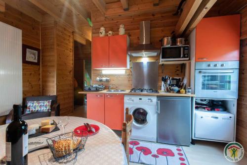 La cuisine est équipée de placards rouges et d'un four avec plaques de cuisson. dans l'établissement Le Petit Renard, à Ancelle