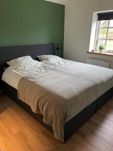 a large bed in a bedroom with a window at Appartementen Chaamse Bossen met tuin in Chaam