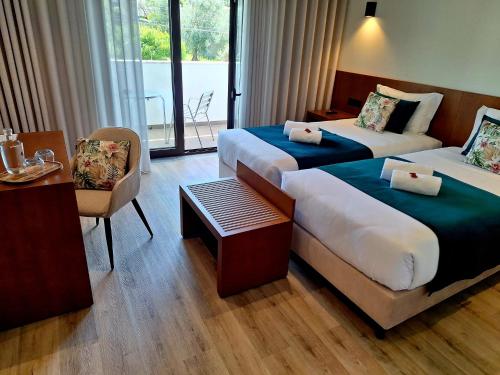 a hotel room with two beds and a table at 3M Hostel & Suites in Alvaiázere