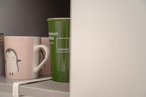two coffee cups sitting on top of a shelf at Le Village Aewol building A in Jeju