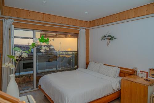 a bedroom with a bed and a large window at Le Village Aewol building A in Jeju