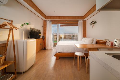 a bedroom with a bed and a table and a kitchen at Le Village Aewol building A in Jeju