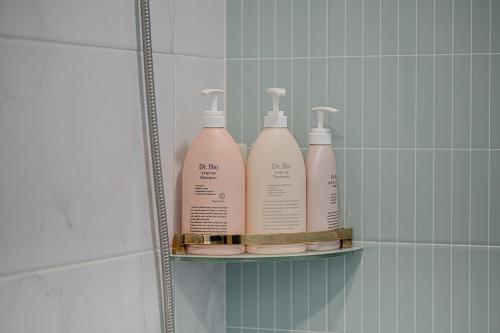a shelf with four bottles of cleaning products on it in a bathroom at Le Village Aewol building A in Jeju