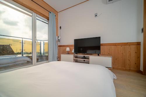 a bedroom with a large bed and a large window at Le Village Aewol building A in Jeju