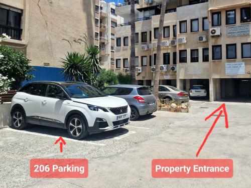 two cars parked in a parking lot in a city at Lazaros Centre Apartment in Larnaka