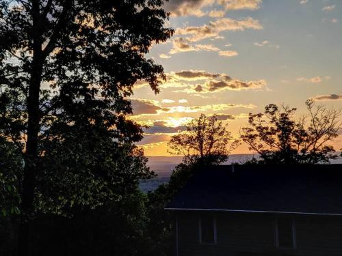 a sunset behind two trees and a house at Multi-gen Family Mountain House in Front Royal