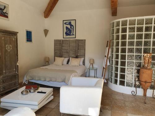 une chambre avec un lit, un canapé et une chaise dans l'établissement Mas au Cœur de La Provence & SPA, à Saint-Cannat