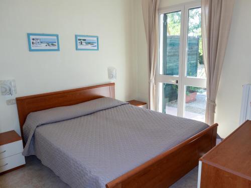 a bedroom with a bed and a large window at agriturismo I Gelsi Marina di Grosseto in Marina di Grosseto