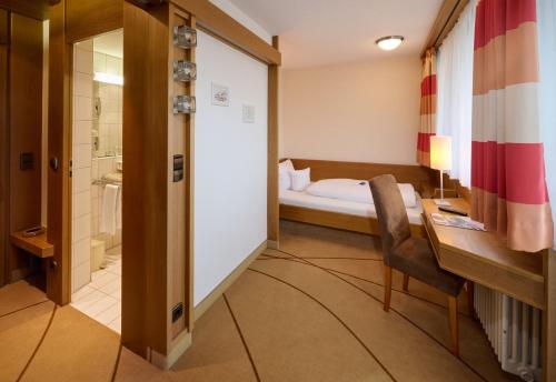 a bathroom with a bed and a desk and a chair at Hotel Schönbuch in Pliezhausen