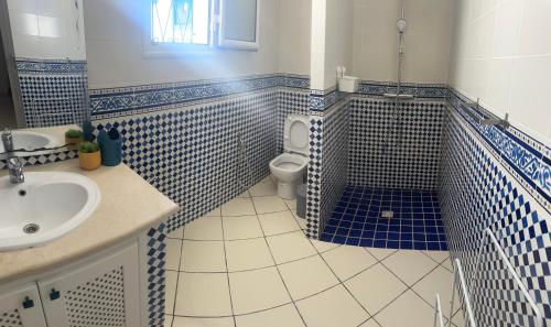 a bathroom with blue and white tiled walls and a toilet at Kmi in Zarzis