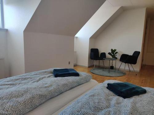 twee bedden in een kamer met twee stoelen en een tafel bij Rummelig lejlighed - i Dronninglund in Dronninglund
