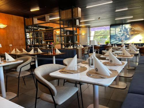 un restaurant avec des tables, des chaises et un écran dans l'établissement HOTEL DE LA GARE, à Eygliers