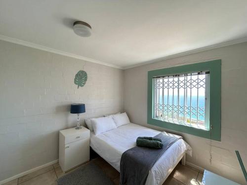 a small bedroom with a bed and a window at Baydream Away in Cape Town