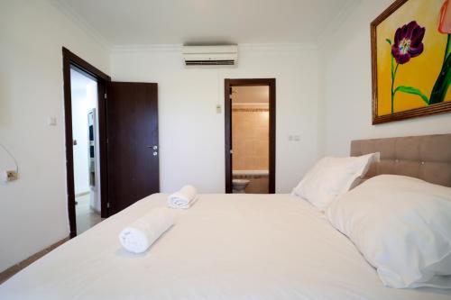 a bedroom with a white bed with two towels on it at Central Park Residence in Eilat