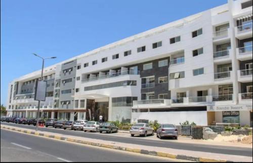 a large white building with cars parked in front of it at Scanddic Resort Hurghada in Hurghada