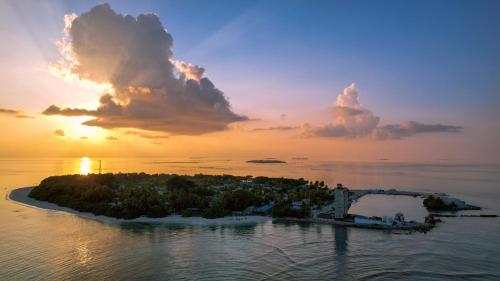 an island in the ocean with a sunset at Hanifaru Beach Inn in Baa Atoll