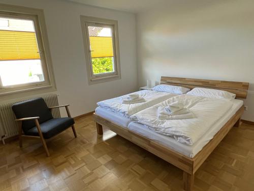 a bedroom with a bed and a chair and two windows at Haus Anna in Freudenstadt