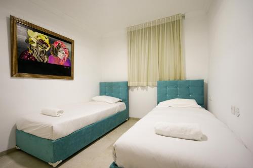 a bedroom with two beds and a picture on the wall at Central Park Residence in Eilat