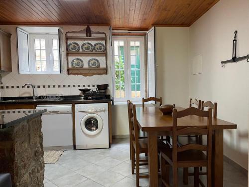 a kitchen with a table and a washing machine at Casa Retiro de Xisto in Videmonte