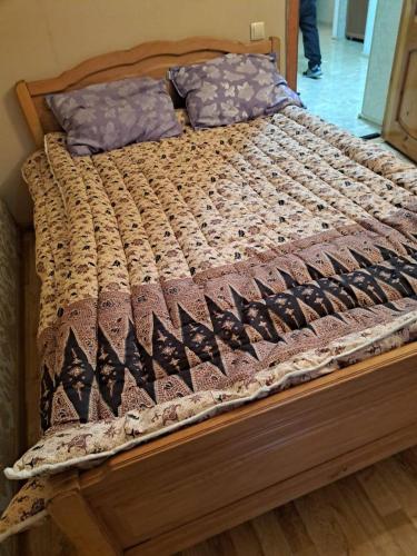 una cama de madera con una colcha encima en Cosy House, en Akhaltsikhe