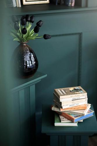 a stack of books sitting on a table next to a vase with flowers at Alpstay - Chalet Hotel Hartmann - Adults Only in Ortisei