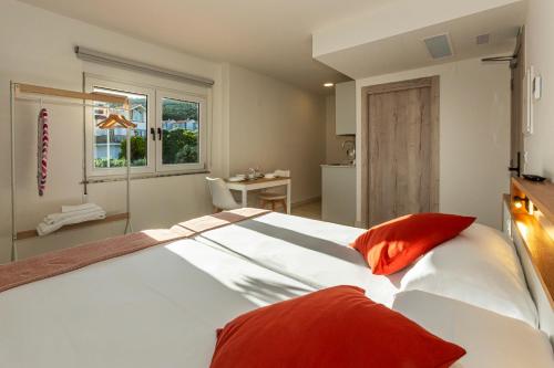 フィステーラにあるOla Apartamentos Finisterreの大きな白いベッドと赤い枕のある寝室