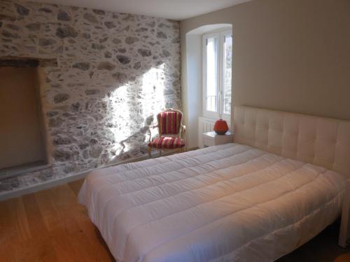 - une chambre avec un lit dans une pièce dotée d'un mur en pierre dans l'établissement Saint Christophe, à Omessa