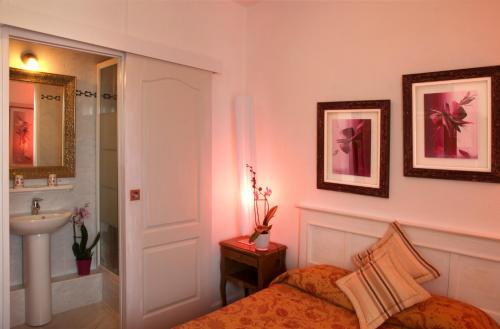 a bedroom with a bed and a sink and a mirror at Chez Madame Cailleau in Houlgate