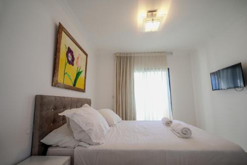 a bedroom with a bed with white sheets and a window at Central Park Residence in Eilat