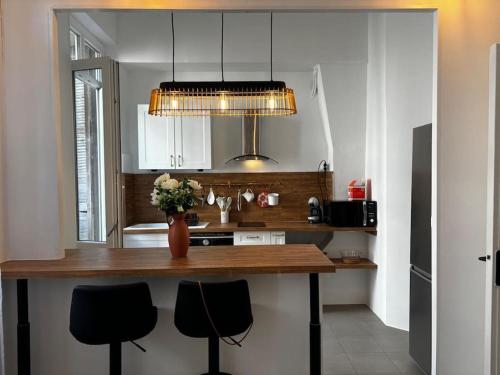 une cuisine avec un comptoir avec deux chaises et un vase de fleurs dans l'établissement Confort et style en plein Marseille Type 2, à Marseille
