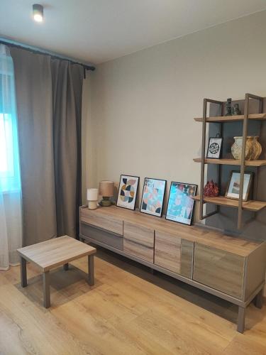 a living room with a shelf with pictures and a table at Žemaičių 8 in Kretinga
