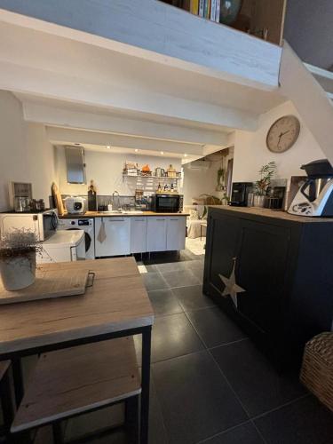 une grande cuisine avec une table et une horloge murale dans l'établissement Studio RDC terrasse , climatisé, tout confort, à Lunel