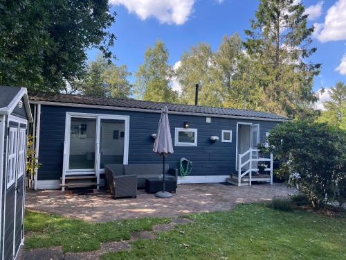 a blue house with a patio and an umbrella at Modern chalet in de bossen van de Veluwe in Epe