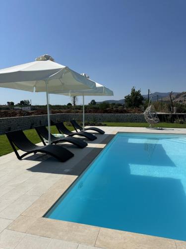 a swimming pool with chairs and an umbrella at Villa Arancia in Argos
