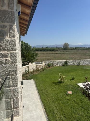 a backyard with a stone wall and a grass yard at Villa Arancia in Argos