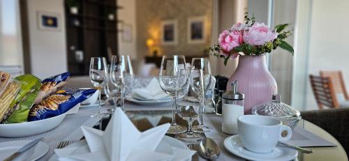 a table with glasses and a vase with pink flowers at Apartment Holata 401 in Hradec Králové